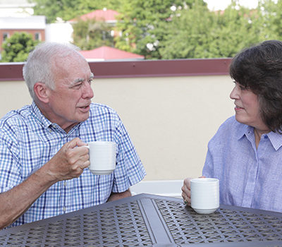 An older couple shares coffee outside at Linden House Assisted Living at Branchlands