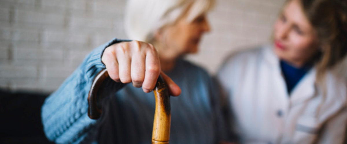 Elder woman with cane and caregiver