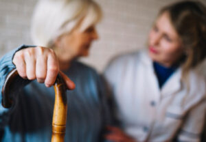 Elder woman with cane and caregiver