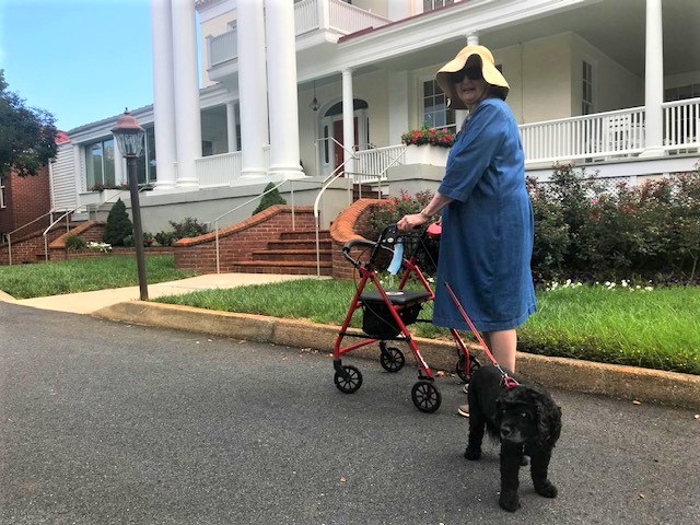 Independent living resident with her pet dog in front of The Manor House