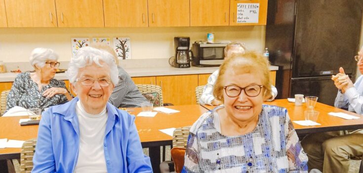 Two smiling women in front of a table at Branchlands retirement community