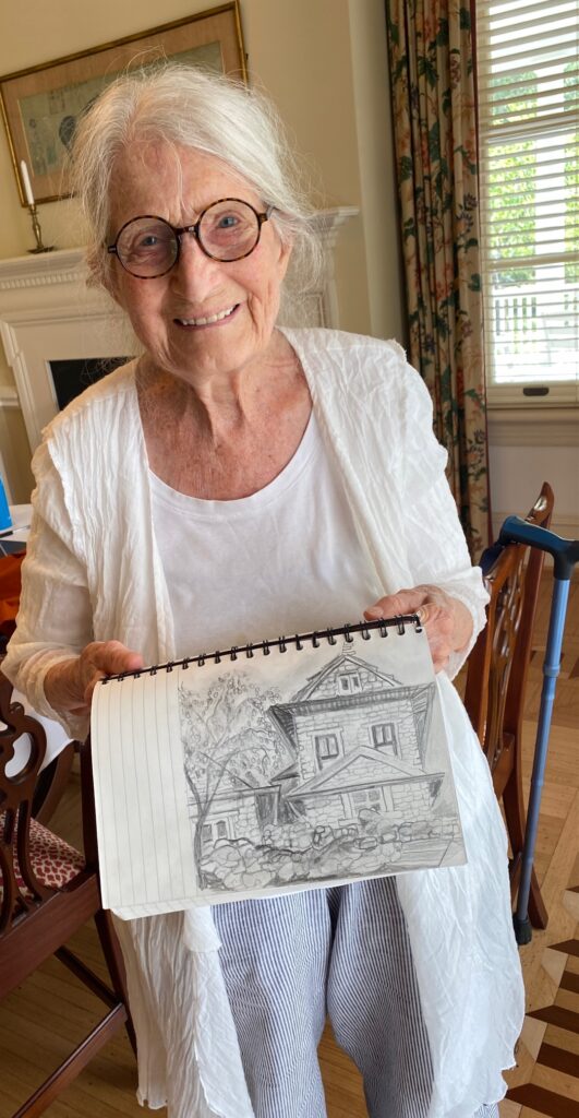 Denise at Branchlands, holding up a sketch of a house from her travels