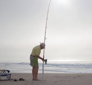 Bill on a beach with a fishing pole