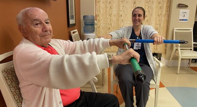 A smiling resident and a Powerback physical therapist work our at Branchlands' rehab gym.