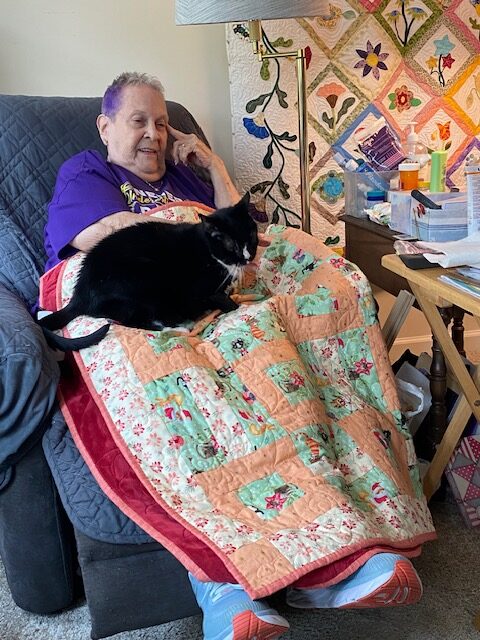 Bobbe with her cat Shadow seated on her lap.