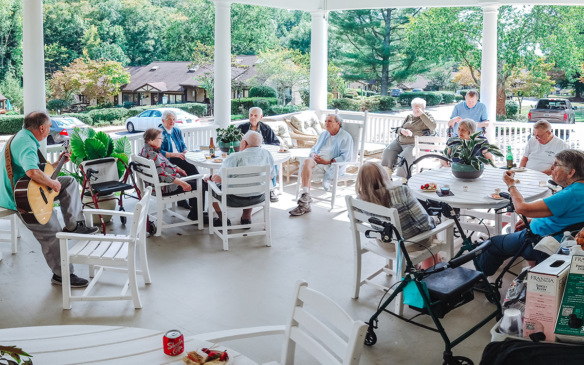 Musician Fritz Horisk playing for Branchlands residents on the porch on a sunny day.