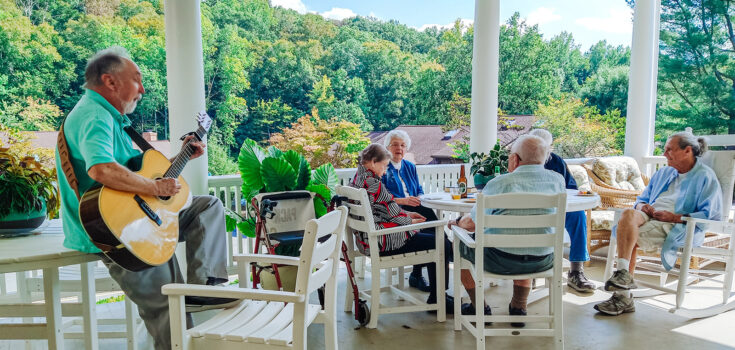 Musician Fritz Horisk playing for Branchlands residents on the porch on a sunny day.