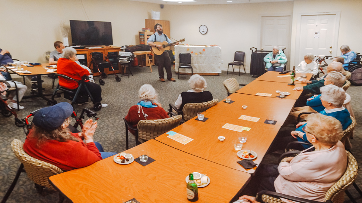 Musician Matthew O'Donnell playing guitar and singing to Branchlands residents.