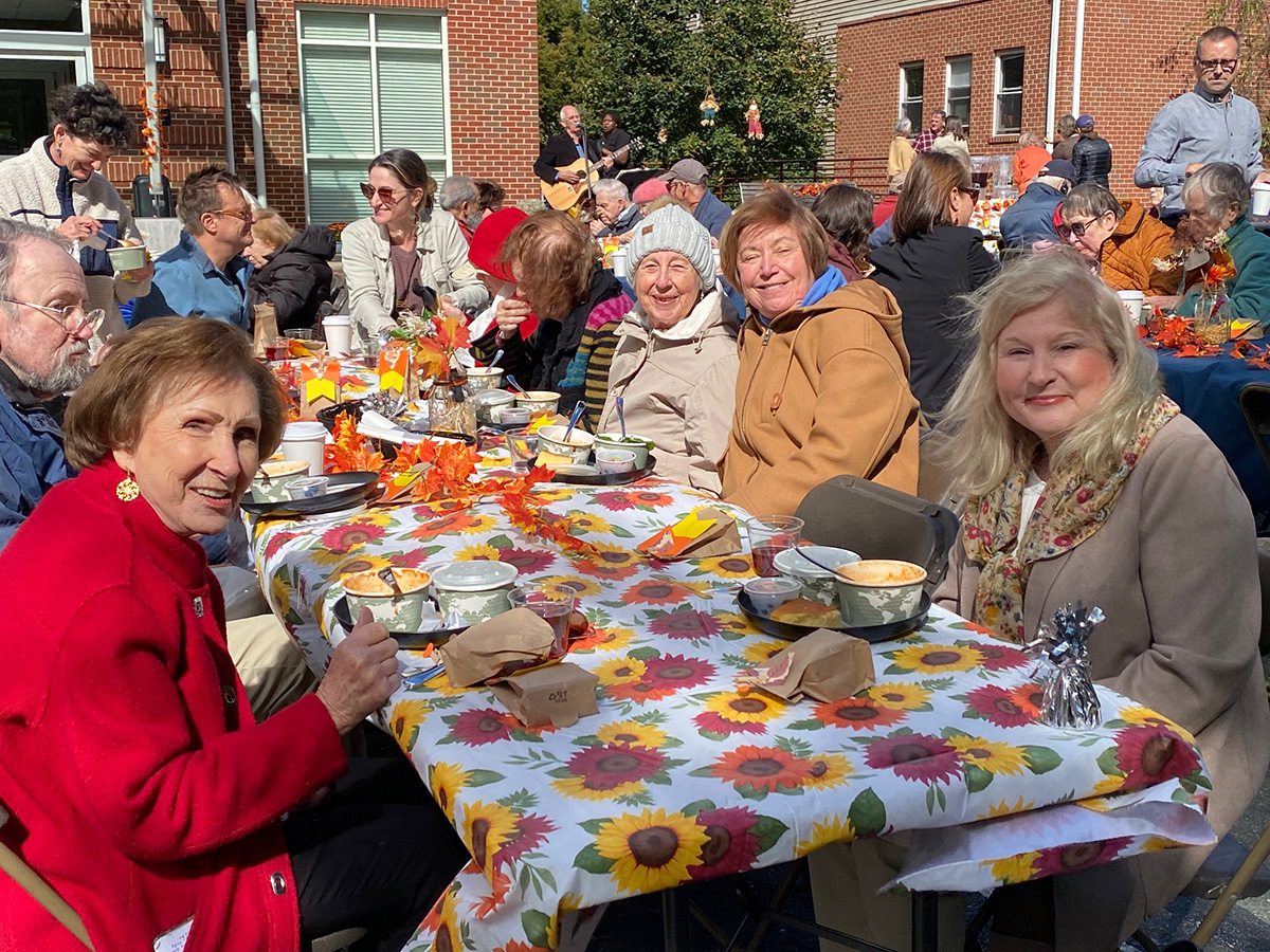 Senior living residents and their families enjoying an outdoor fall meal together.