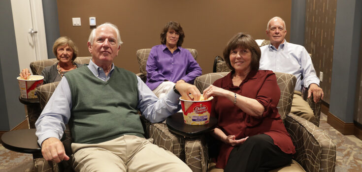 Seniors enjoying a movie with popcorn in the theater room at Branchlands