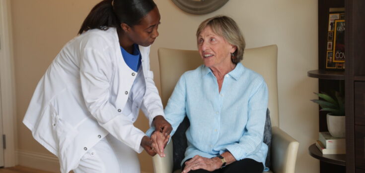 A nurse and a resident in a chair talking